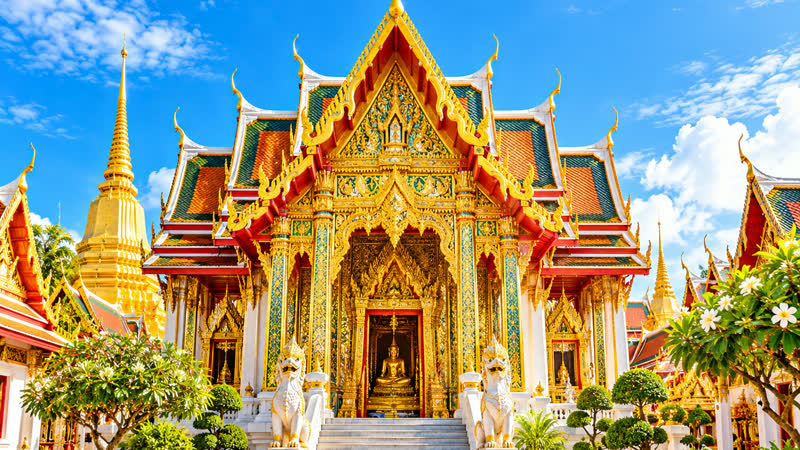 Thai temple with tiered gold and red roofs and a white stairway