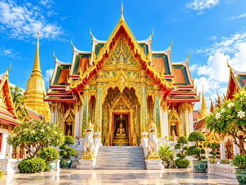 Thai temple with tiered gold and red roofs and a white stairway